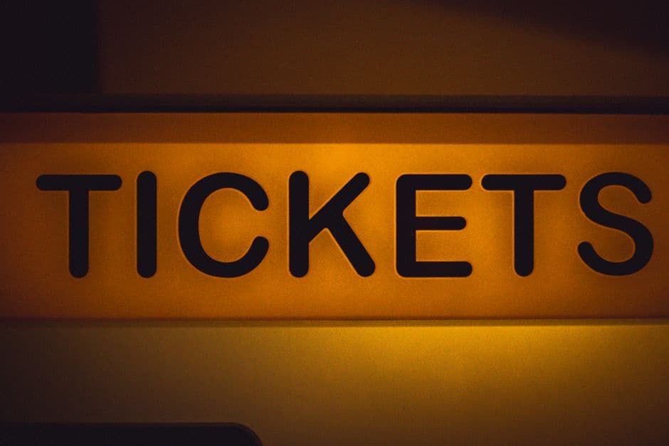 A close-up of a yellow wall sign reading TICKETS