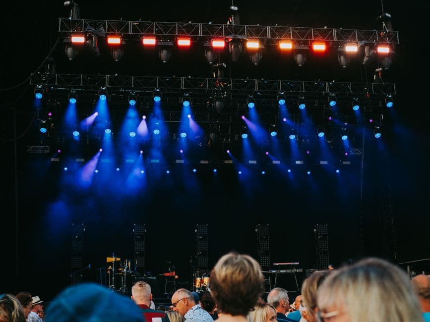 A packed crowd in front of a brightly lit event stage
